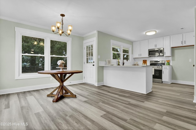 kitchen featuring decorative light fixtures, white cabinets, light hardwood / wood-style floors, kitchen peninsula, and stainless steel appliances