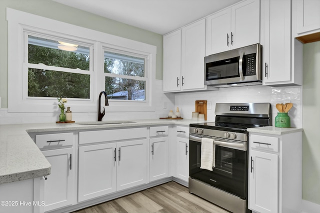 kitchen featuring light stone countertops, white cabinetry, appliances with stainless steel finishes, and sink