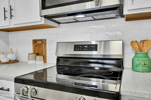 kitchen featuring white cabinetry, decorative backsplash, light stone countertops, and appliances with stainless steel finishes