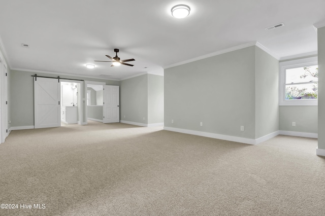 carpeted spare room with crown molding, ceiling fan, and a barn door