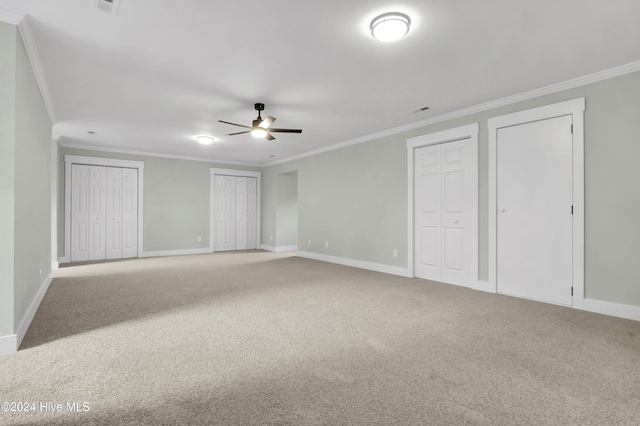 unfurnished bedroom featuring ornamental molding, carpet flooring, two closets, and ceiling fan