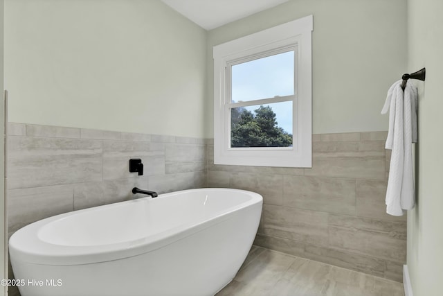 bathroom with a bathing tub and tile walls