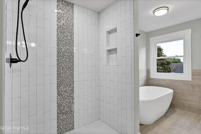 bathroom with shower with separate bathtub and tile walls