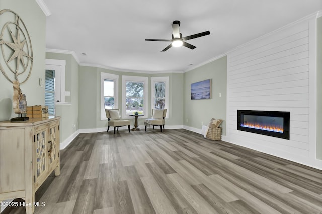 unfurnished room featuring hardwood / wood-style floors, ornamental molding, a large fireplace, and ceiling fan