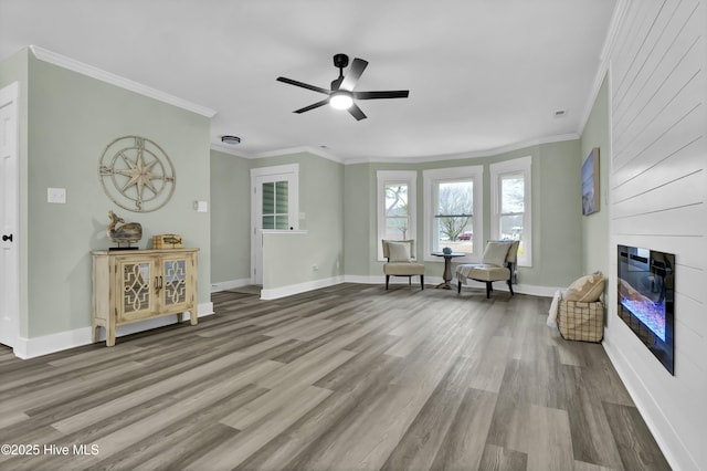 sitting room with wood-type flooring, ornamental molding, a large fireplace, and ceiling fan