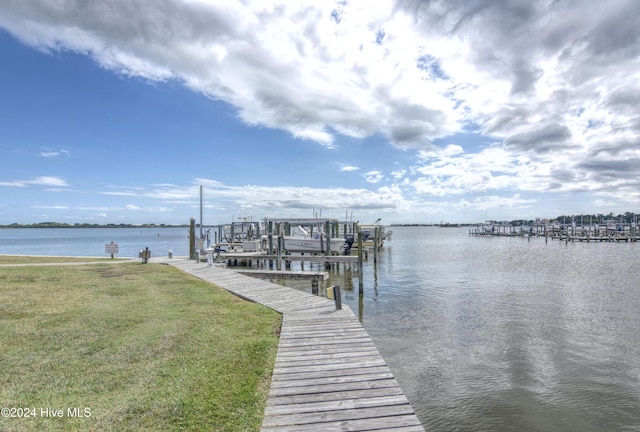 view of dock with a water view and a lawn