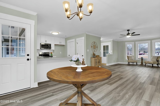 dining area featuring crown molding, ceiling fan with notable chandelier, and light wood-type flooring