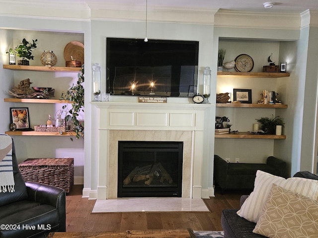 living area with a fireplace with flush hearth, wood finished floors, built in shelves, and ornamental molding