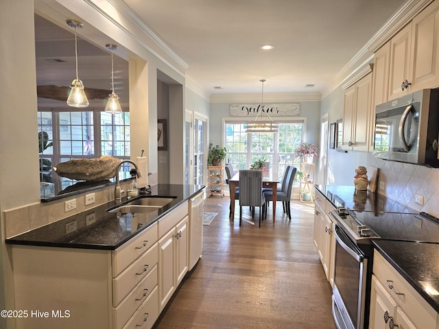 kitchen with tasteful backsplash, ornamental molding, appliances with stainless steel finishes, dark wood-style floors, and a sink