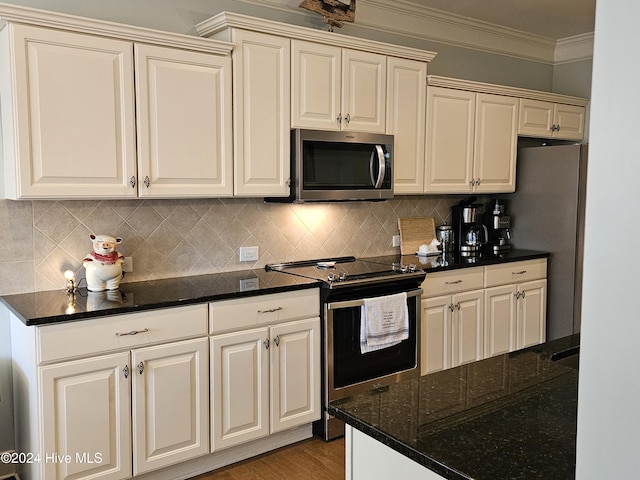 kitchen featuring crown molding, decorative backsplash, light wood-style floors, cream cabinetry, and stainless steel appliances