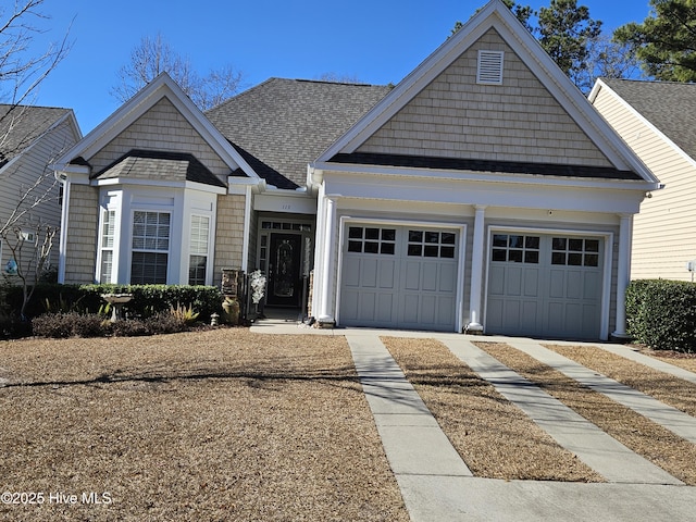 craftsman-style home with concrete driveway, a garage, and roof with shingles