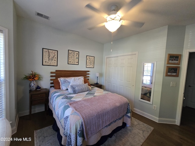 bedroom featuring baseboards, visible vents, dark wood-style flooring, ceiling fan, and a closet