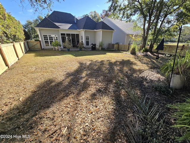 rear view of property featuring a yard and a fenced backyard