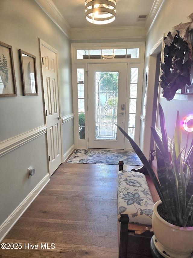 foyer entrance featuring visible vents, baseboards, wood finished floors, and crown molding