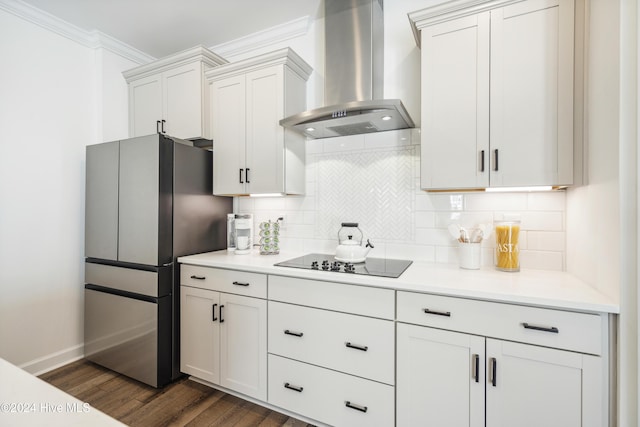 kitchen featuring white cabinetry, wall chimney range hood, black electric stovetop, backsplash, and stainless steel refrigerator