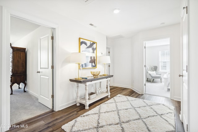 corridor with visible vents, baseboards, and wood finished floors