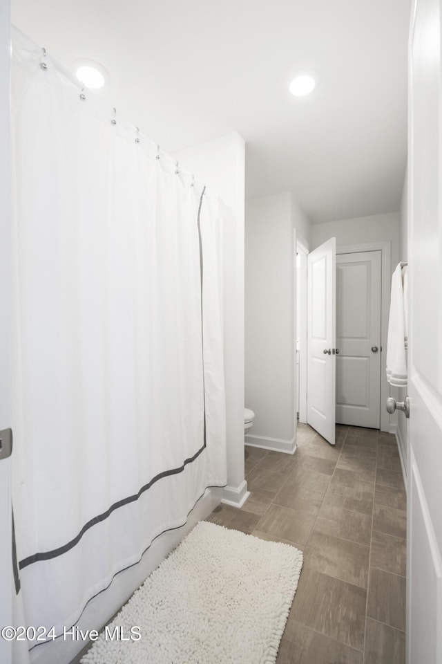 full bathroom featuring toilet, a shower with shower curtain, and baseboards