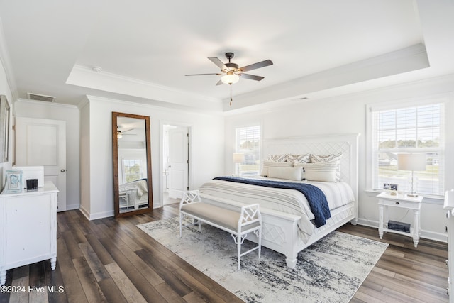 bedroom featuring multiple windows, ceiling fan, dark hardwood / wood-style flooring, and a tray ceiling