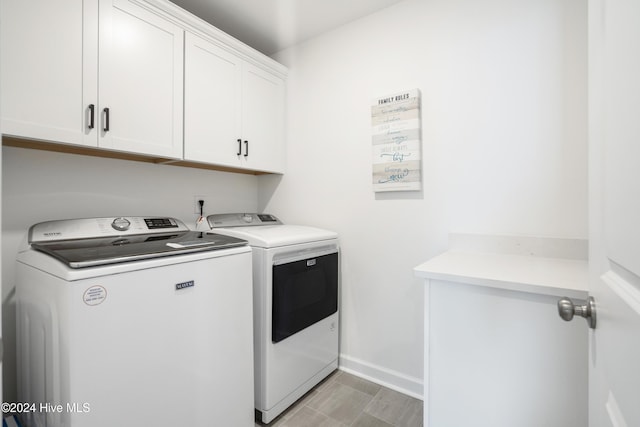 washroom featuring baseboards, cabinet space, and separate washer and dryer