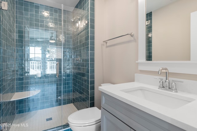 bathroom featuring an enclosed shower, vanity, and toilet