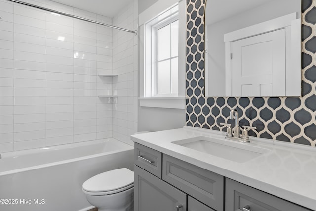 full bathroom featuring vanity, tiled shower / bath, and toilet