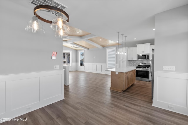 kitchen featuring appliances with stainless steel finishes, dark hardwood / wood-style floors, lofted ceiling with beams, white cabinets, and a kitchen island