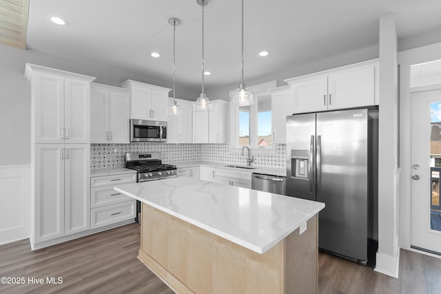 kitchen with sink, white cabinetry, a center island, hanging light fixtures, and stainless steel appliances