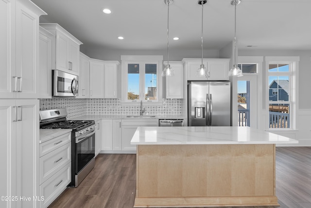 kitchen with stainless steel appliances, hanging light fixtures, a center island, and white cabinets