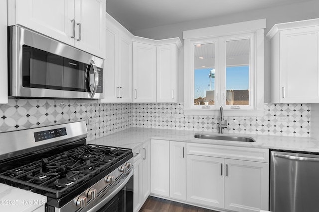 kitchen featuring sink, backsplash, stainless steel appliances, light stone countertops, and white cabinets