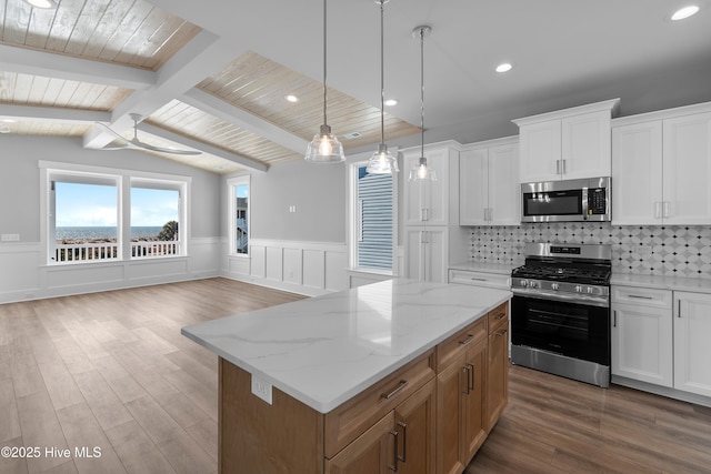 kitchen with white cabinetry, decorative backsplash, a center island, light stone counters, and stainless steel appliances