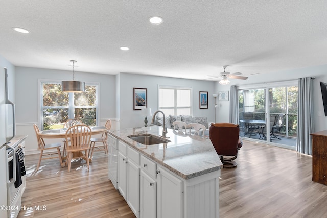 kitchen featuring a wealth of natural light, white cabinetry, sink, and hanging light fixtures