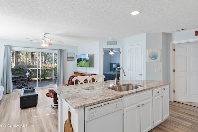 kitchen with white cabinets, sink, white dishwasher, a kitchen island with sink, and light hardwood / wood-style floors