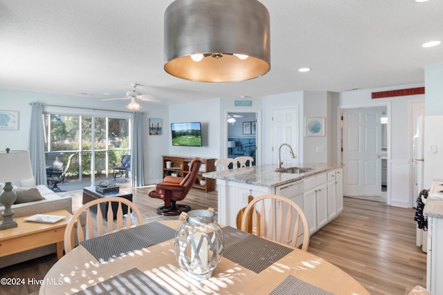 dining space with ceiling fan, sink, and light wood-type flooring