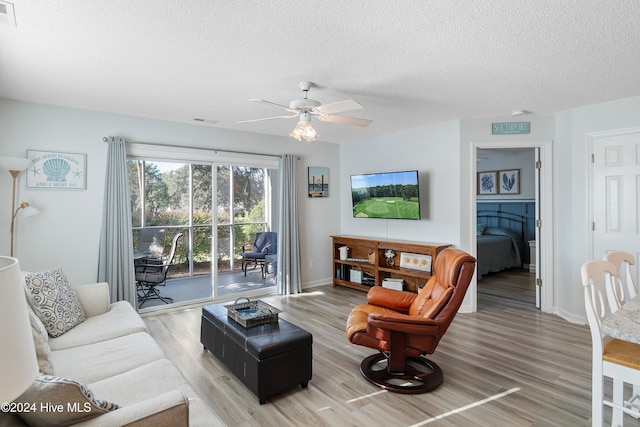 living room with ceiling fan, hardwood / wood-style floors, and a textured ceiling