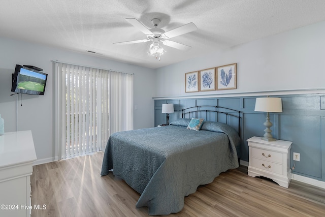 bedroom with a textured ceiling, light wood-type flooring, and ceiling fan