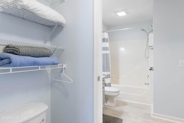 bathroom featuring hardwood / wood-style floors, shower / bath combination with curtain, and toilet