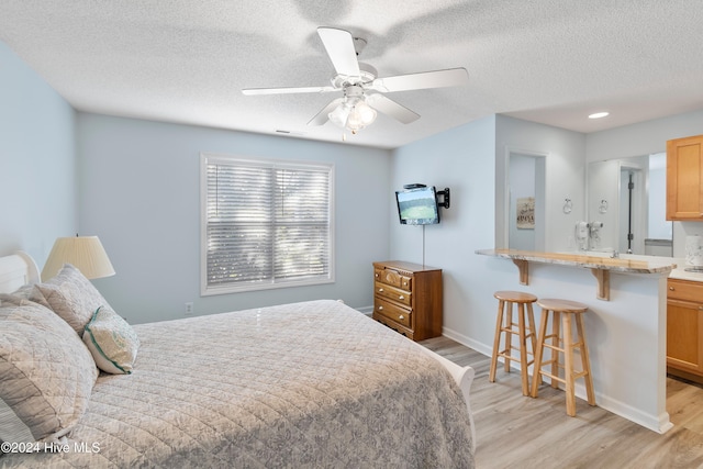 bedroom with ceiling fan, a textured ceiling, and light wood-type flooring