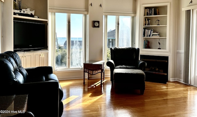 sitting room with built in shelves, a healthy amount of sunlight, and light hardwood / wood-style floors