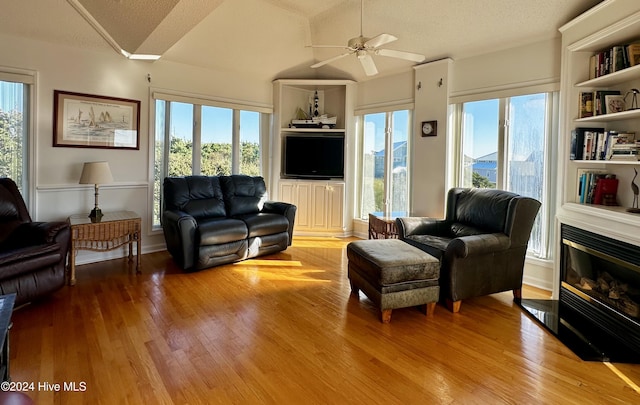 living room with built in shelves, a textured ceiling, and light hardwood / wood-style flooring