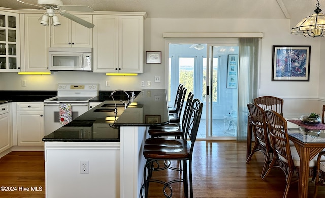 kitchen with dark hardwood / wood-style flooring, white cabinets, hanging light fixtures, and white appliances