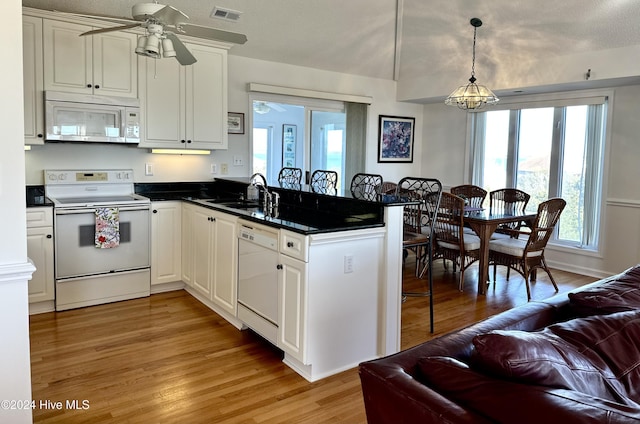 kitchen featuring kitchen peninsula, white cabinetry, sink, and white appliances