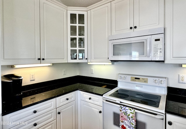 kitchen with white cabinets, dark stone countertops, white appliances, and a textured ceiling