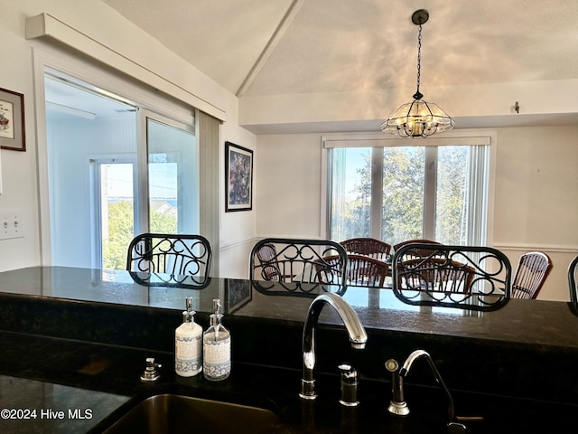 dining space featuring a chandelier, vaulted ceiling, and sink