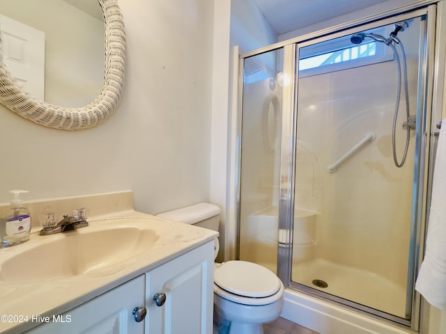 bathroom with tile patterned flooring, vanity, toilet, and walk in shower