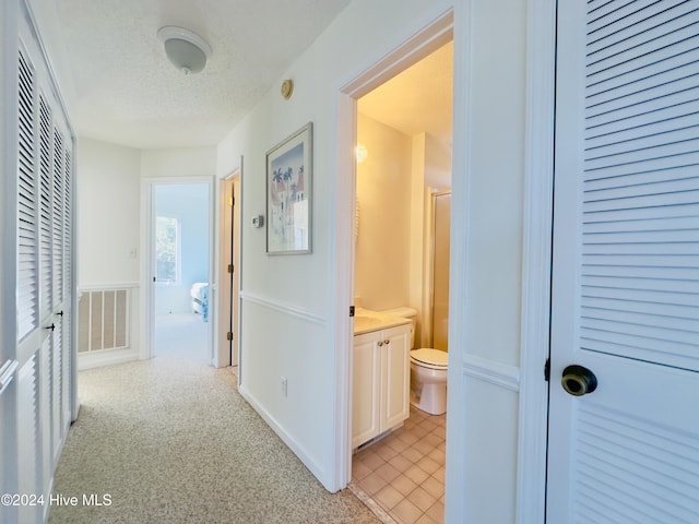 corridor featuring light carpet and a textured ceiling