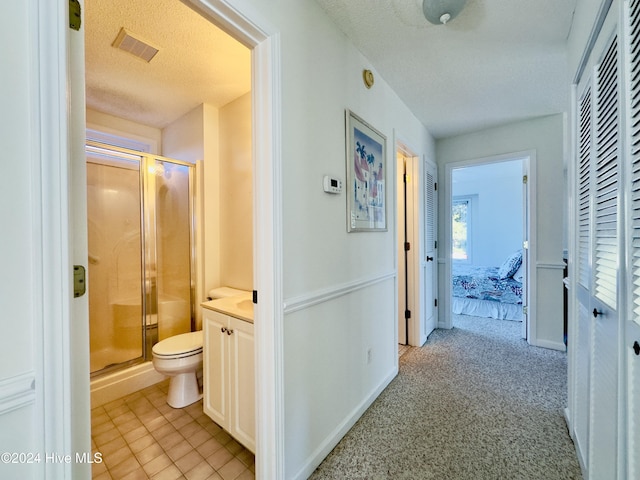 hall featuring a textured ceiling and light colored carpet