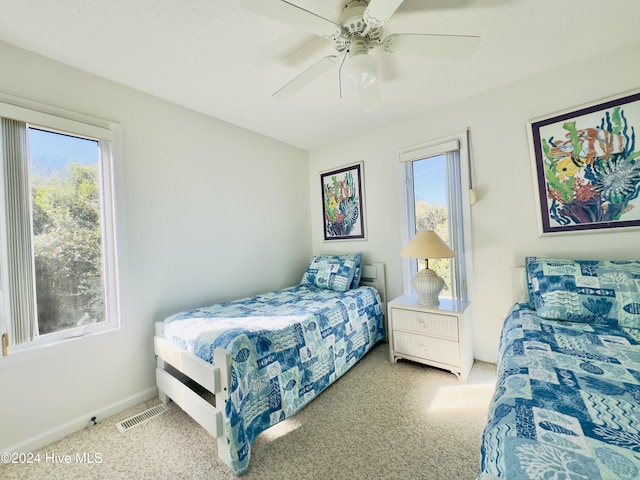 bedroom featuring multiple windows, ceiling fan, and light colored carpet