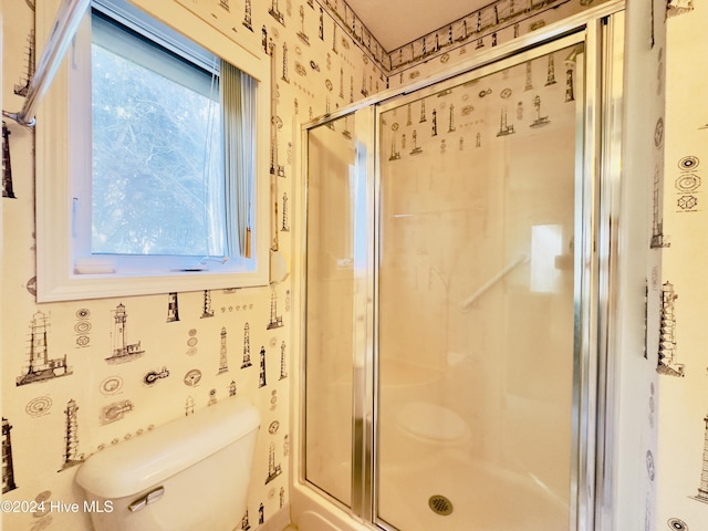 bathroom featuring a shower with shower door and toilet