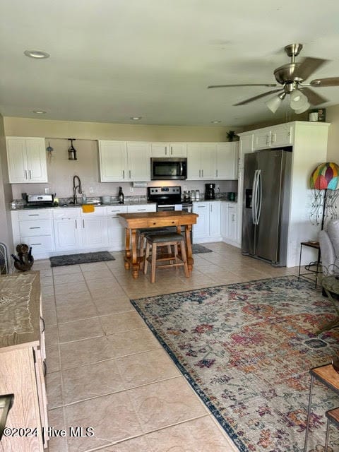 kitchen featuring light tile patterned floors, sink, ceiling fan, white cabinetry, and appliances with stainless steel finishes