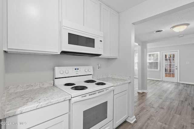 kitchen featuring white cabinetry, light wood-type flooring, a textured ceiling, and white appliances